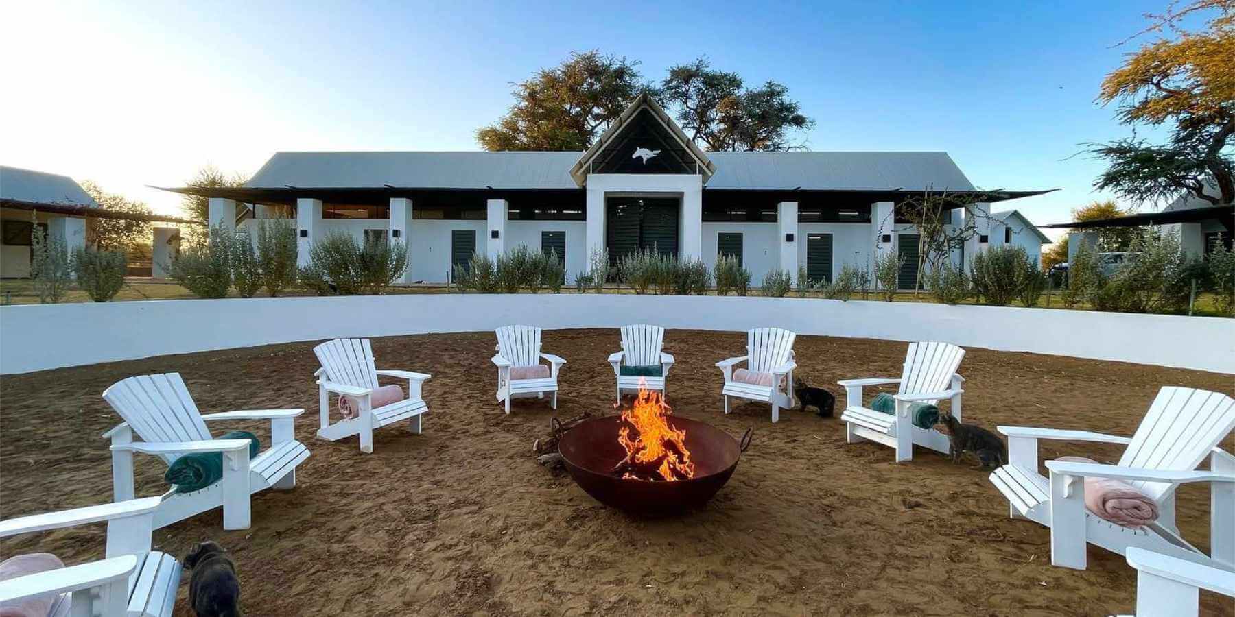 In preparation for a group session on the grounds of Sandwerf, white chairs surround an open fire.